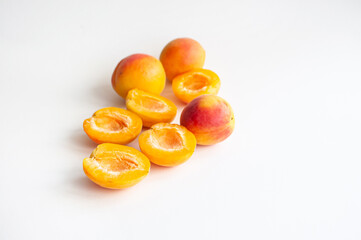 Sweet ripe cut and whole apricots with a seed on white background with copyspace.