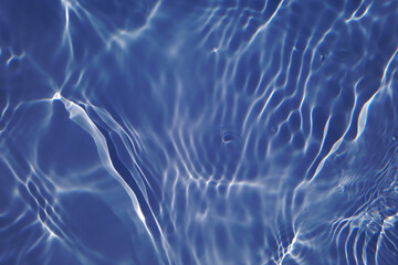 Bluewater waves on the surface ripples blurred. Defocus blurred transparent blue colored clear calm water surface texture with splash and bubbles. Water waves with shining pattern texture background.