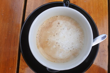 Cup of coffe with milk on a wooden dark table background. Hot Cappuccino prepared with milk on a wooden table with copy space