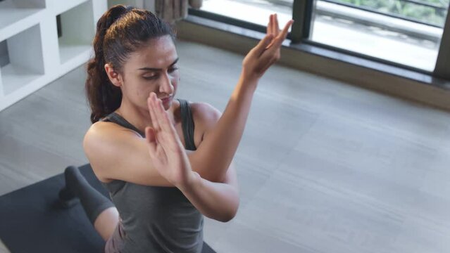 Young Beautiful fit Indian Asian girl or female performing advanced yoga posture Garudasana (Seated Eagle pose) in interior house. Fitness, health, wellness, exercise concept