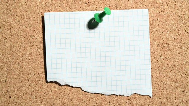 Papel recortado clavado con un pin de color verde en el tablero