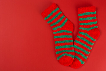 Two green striped Christmas socks, as if standing on toes, on a red background, concept