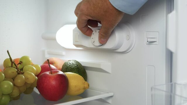 Man Hand Open the Kitchen Fridge Door and Set the Thermostat. Making the Fridge Temperature Control for Optimum Function.
