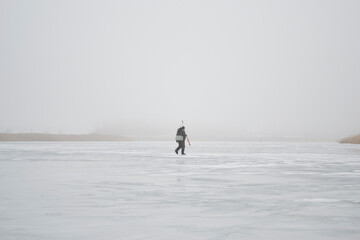 Fototapeta na wymiar Lonely fisherman on the lake in winter mist