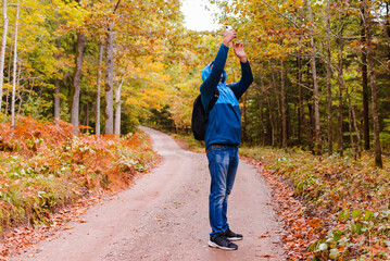 Man hiker stands in a beautiful autumn forest and catches a mobile network on a smartphone.Tourist looking for a cellular connection on a hike, raised his phone up.Travel Technology concept.