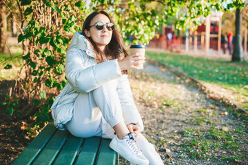 Woman drinking coffee sitting on the bench