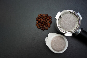 horn - holder, coffee pod and coffee beans on a black slate board.