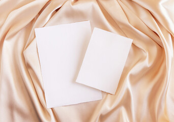 Blank cards on beige silky fabric drapery top view, greeting or wedding mockup