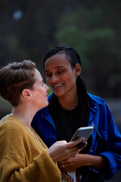 Smiling female couple using smart phone outdoors