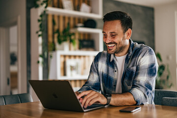 Happy man working from home over the laptop, typing on the keyboard.