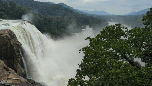 beautiful and majestic waterfalls at the center of a deep green forest surrounded by hills and mountains 