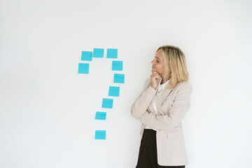 Businesswoman looking at question mark on the wall