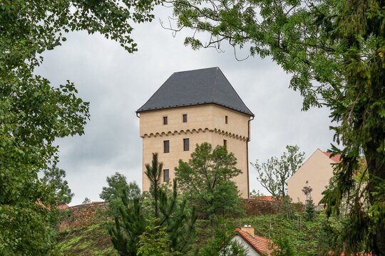 Kralovice, Prague, Czech Republic - August 28 2022: View of the renewed yellow tower of the former fortress from the 14th century standing on a hill surrounded with green trees and houses.