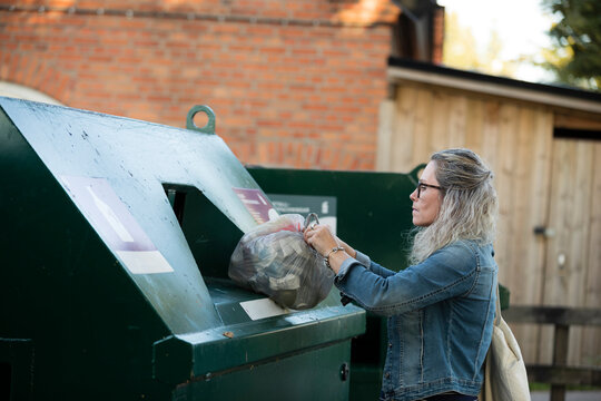 Blond woman throwing rubbish into waste bin