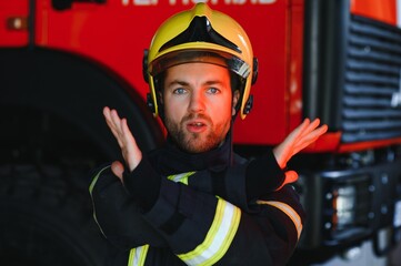 Fototapeta premium Firefighter portrait on duty. Photo fireman with gas mask and helmet near fire engine.