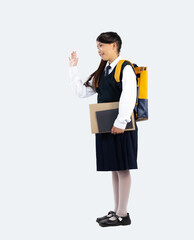 Back to school concept. Junior school girl in british student uniform posing goodbye on white background with full length.
