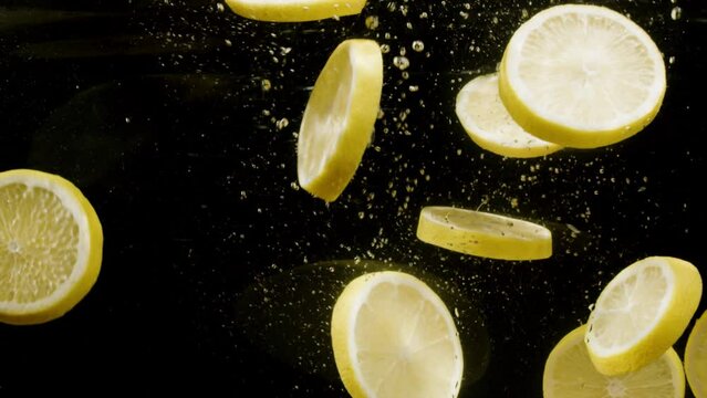 pieces of sliced lemon fall into the water, slow motion