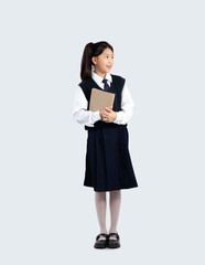 Elementary school kid in student uniform holding book standing on white background. Back to shcool concept.
