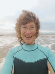 Mature woman takes a selfie before cold water swimming. Open, wild or cold water swimming in the sea is known to have benefits for physical and mental health. The weather is rough.