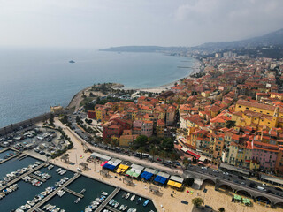 Fototapeta premium Aerial view of Menton in French Riviera from above. Drone view of France Cote d'Azur sand beach beneath the colorful old town of Menton. Small color houses near the border with Italy, Europe.