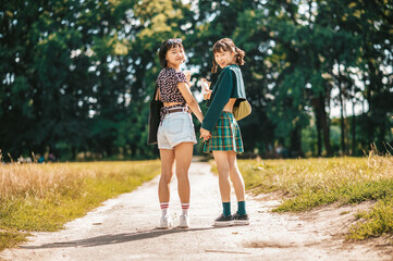 Fototapeta premium Young pretty girls walking in the park and holding hands