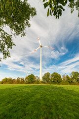 low angle view of  a wind turbine on the field  against the blue sky with the white clouds