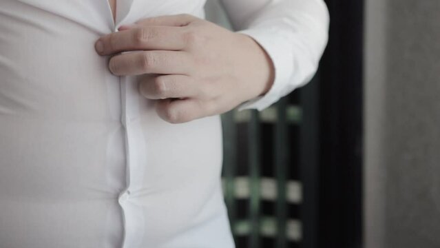 A man in a white shirt holds a cigarette in his hand against the background of his stomach and throws it away, on which an anti-smoking patch is pasted. Fight against smoking. Harm of nicotine. Slow