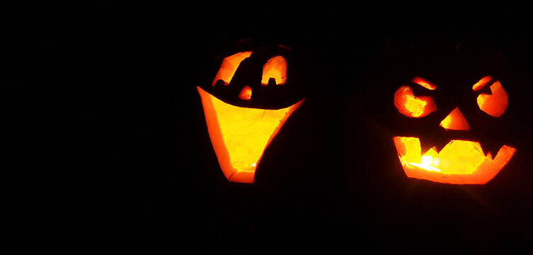 Carved Halloween pumpkin face with candle inside glowing in the darkness