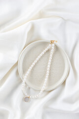 Necklace made of natural pearls on a white silk background.