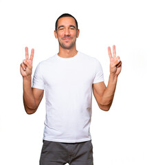 Naklejka premium Happy young man making a victory gesture with his fingers