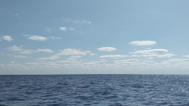 Small private luzzu boat with people in life jackets traveling in beautiful blue open mediterranean sea with calm waves and scenic panorama view on a beautiful sunny day
