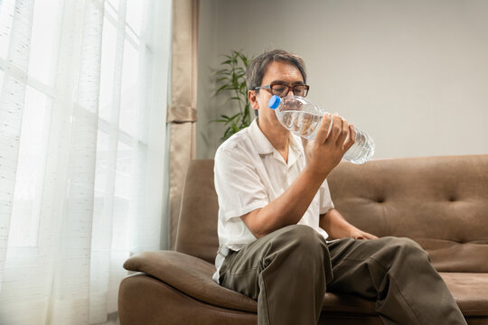 Senior Asian Man Workout Water Bottle At Home To Preserve His Muscle Mass, Prevent Sarcopenia And Bone Resorption.