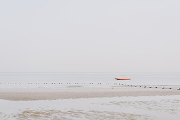 Small red boat at the beach during low tide early in the morning - 537493711