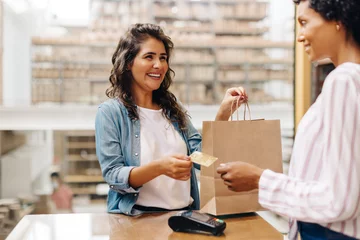 Foto op Plexiglas Happy female customer paying with a credit card in a ceramic store © (JLco) Julia Amaral