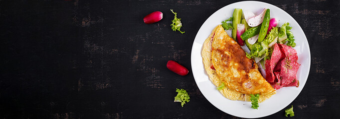 Breakfast. Omelette with cheese and  fresh salad, salami. Frittata - italian omelet. Ketogenic lunch. Top view, banner