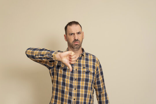 Handsome 40 Years Old Man Over Isolated Beige Background Looking Unhappy And Angry Showing Rejection And Negative With Thumbs Down Gesture. Bad Expression