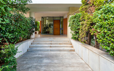 A contemporary residential apartment building main entrance marble stairway and a wooden door. Athens, Greece.