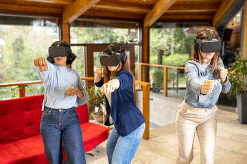 three young women enjoy virtual reality in the living room, female friends using new technologies for gaming, simulated martial arts moves with headsets for augmented reality