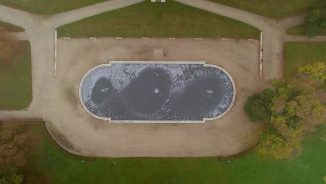 A zoom in shot of a beautiful reservoir where fountains are seen in day time. An amazing view has been captured through drone
