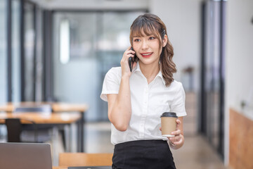 Informal Call. Happy young Asian woman in workplace calling her friend, talking and asking about something, using laptop