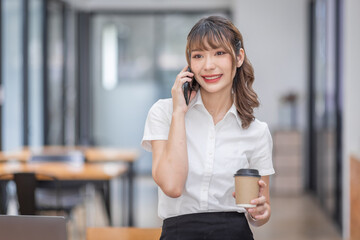 Informal Call. Happy young Asian woman in workplace calling her friend, talking and asking about something, using laptop