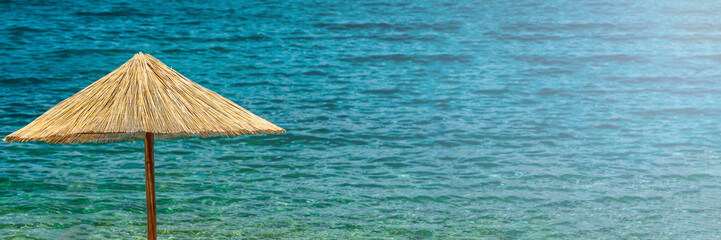 Panorama of parasol made of straw in front of blue sea