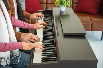 Man and woman playing electronic digital piano wearing winter clothing, no face.