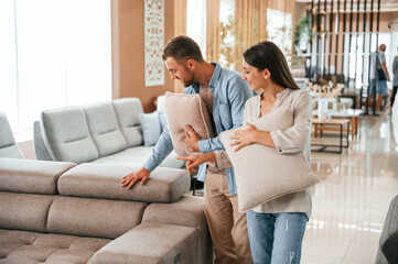 Fototapeta premium Having fun by choosing the sofa. Couple is in the store
