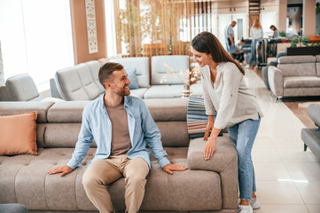 Obraz premium Sitting and relaxing. Couple choosing the sofa and bed in the store