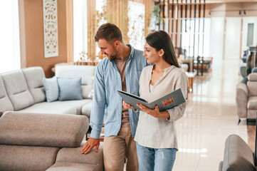 Talking with each other. Couple choosing the sofa and bed in the store