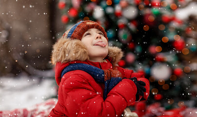 Child catch snowflakes with tongue. Christmas and New Year tree cozy. Concept of childhood and happiness. New Year Christmas holiday. Happy kid playing with snow outdoor. Holidays winter season.