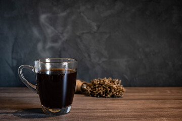 Black hot americano coffee with steam in clear cup on wooden desk with  dark loft style walk  background
