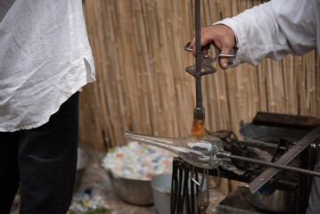 Detalle de unas manos de hombre adulto elaborando de manera artesanal vidrio soplado en el mercado medieval callejero del pueblo de Hondarribia en el País Vasco