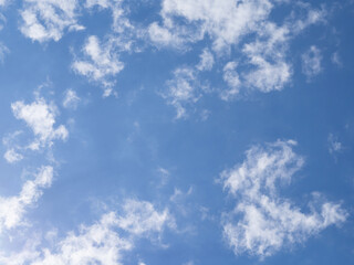 Blue sky and light white clouds illuminated by light on a sunny day. Amazing sky background for design or wallpaper